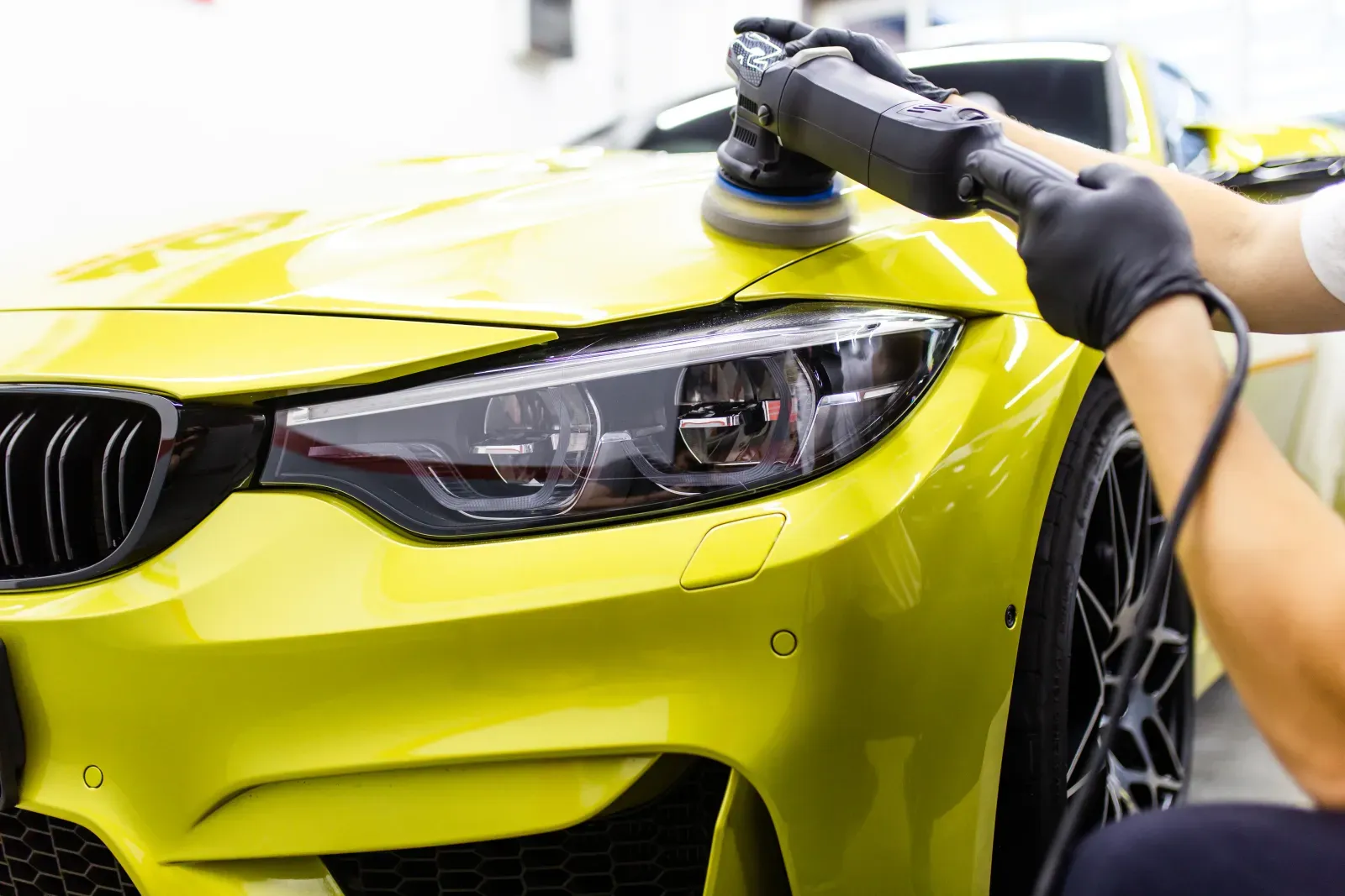 Machine polishing a yellow BMW during paint correction