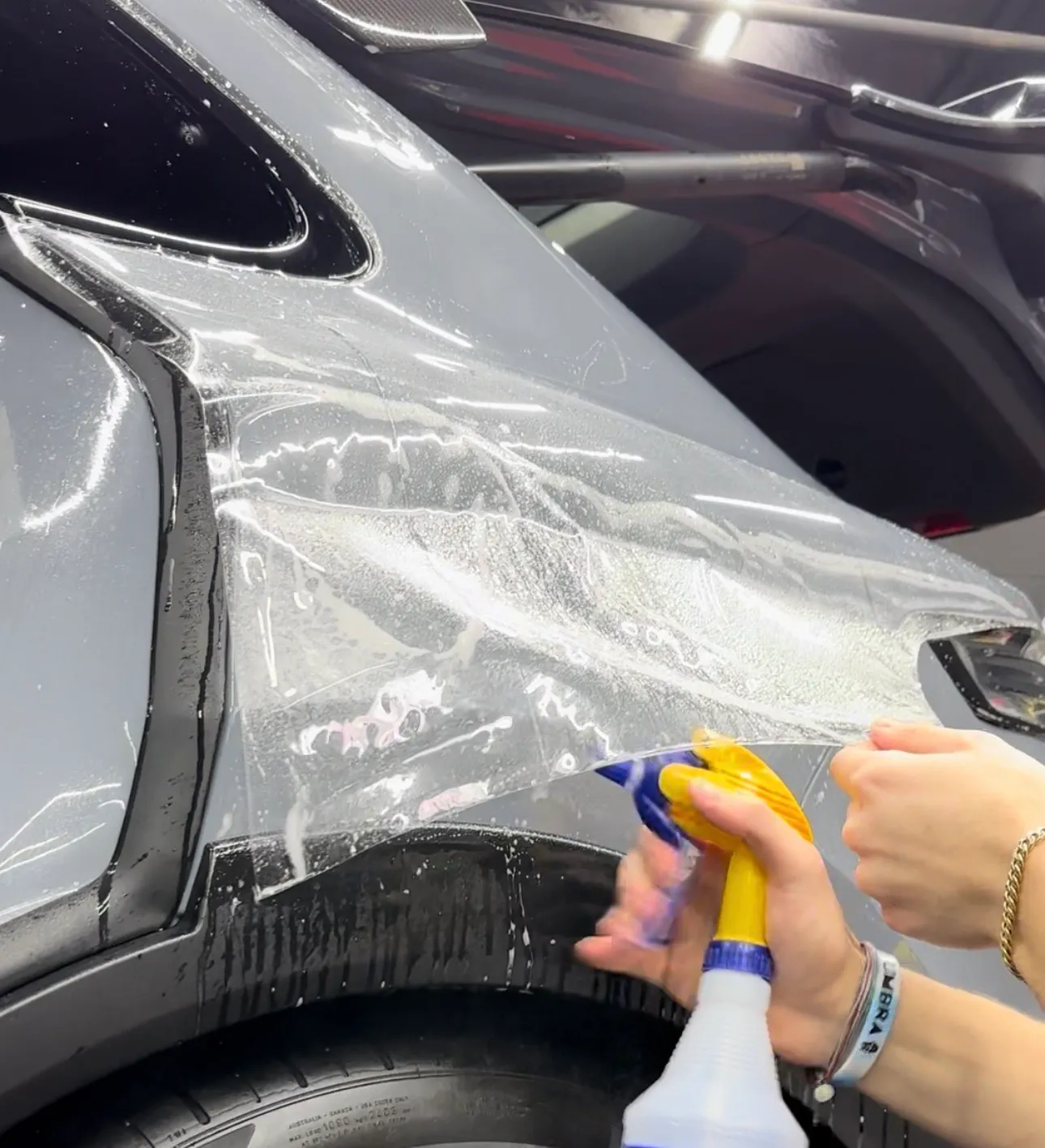 PPF being installed on the rear quarter panel of a gray SUV
